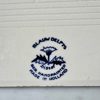 Blue Blauw Delfts Distel logo and text on a white background on back of tile