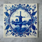 Delft blue tile with a windmill design on a marble surface