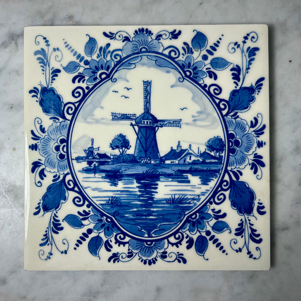 Delft blue tile with a windmill design on a marble surface