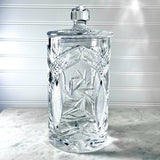 Vintage Zawiercie Laurencie Cut Glass Tall Crystal Cracker Jar with a matching lid, featuring geometric and starburst patterns, set on a marble surface against a white paneled background.